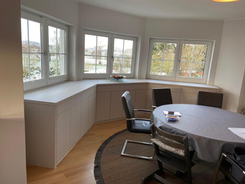 Holzschrank in weiß unter Fenstern