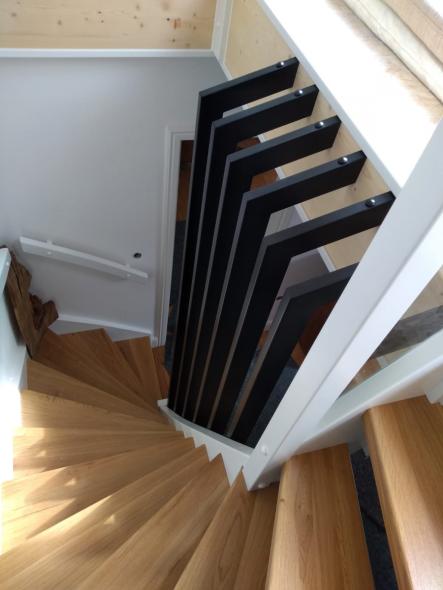 Gewendelte Holztreppe mit weiß/schwarzem Geländer